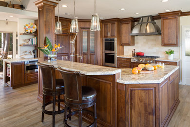 Example of a large classic l-shaped porcelain tile and brown floor eat-in kitchen design in San Diego with a farmhouse sink, raised-panel cabinets, dark wood cabinets, granite countertops, beige backsplash, paneled appliances, an island, subway tile backsplash and beige countertops