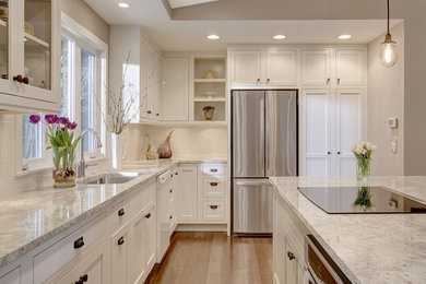 Kitchen - transitional l-shaped kitchen idea in Seattle with an undermount sink, shaker cabinets, white cabinets, stainless steel appliances, an island and window backsplash