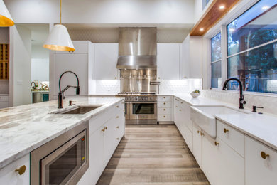 Example of a large transitional l-shaped vinyl floor and brown floor open concept kitchen design in Dallas with white cabinets, marble countertops, white backsplash, an island, a farmhouse sink, porcelain backsplash, stainless steel appliances and multicolored countertops