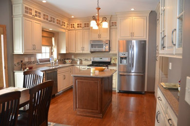 Eat-in kitchen - mid-sized transitional medium tone wood floor and brown floor eat-in kitchen idea in Other with stainless steel appliances, an island, a double-bowl sink, raised-panel cabinets, white cabinets and granite countertops
