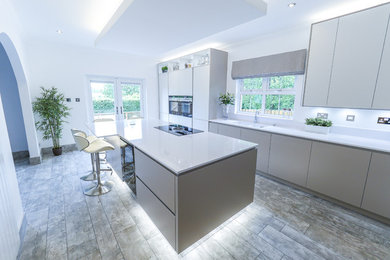 Inspiration for a large contemporary single-wall kitchen/diner in Glasgow with a single-bowl sink, glass-front cabinets, white cabinets, marble worktops, white splashback, glass sheet splashback, white appliances, ceramic flooring, an island and multi-coloured floors.