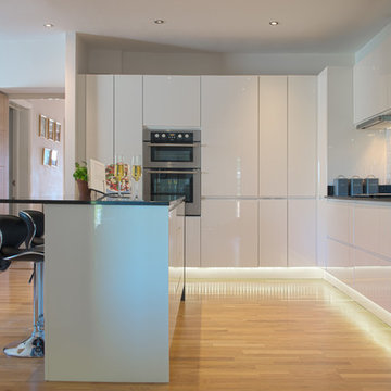 Open plan high gloss white slab door kitchen with black quartz