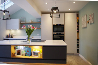 This is an example of a medium sized modern kitchen/diner in West Midlands with composite countertops, stainless steel appliances and an island.