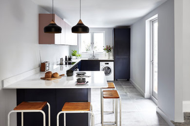 Inspiration for a medium sized scandinavian u-shaped kitchen in London with flat-panel cabinets, composite countertops, ceramic flooring, a breakfast bar, grey floors, white worktops, a submerged sink and black cabinets.