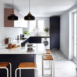 Inspiration for a mid-sized scandinavian u-shaped kitchen in London with flat-panel cabinets, solid surface benchtops, ceramic floors, a peninsula, grey floor, white benchtop, an undermount sink and black cabinets.