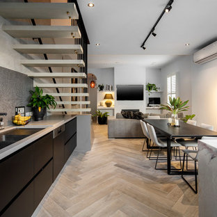 Mid-sized contemporary single-wall open plan kitchen in Melbourne with an undermount sink, black cabinets, marble benchtops, black splashback, mosaic tile splashback, stainless steel appliances, light hardwood floors and with island.