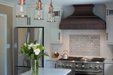 Elegant l-shaped painted wood floor and brown floor eat-in kitchen photo in Toronto with an island and white cabinets