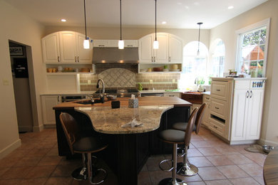 Example of a mid-sized transitional l-shaped terra-cotta tile and brown floor eat-in kitchen design in Miami with a farmhouse sink, raised-panel cabinets, white cabinets, granite countertops, brown backsplash, subway tile backsplash and an island