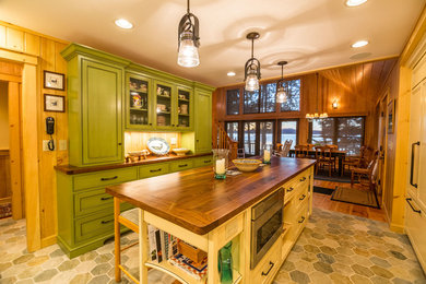 Open concept kitchen - mid-sized rustic galley slate floor and multicolored floor open concept kitchen idea in Portland Maine with beaded inset cabinets, distressed cabinets, wood countertops, beige backsplash, travertine backsplash, paneled appliances and an island