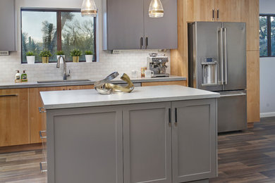 Example of a mid-sized minimalist l-shaped gray floor open concept kitchen design in Phoenix with an undermount sink, shaker cabinets, gray cabinets, quartzite countertops, white backsplash, porcelain backsplash, stainless steel appliances, an island and gray countertops