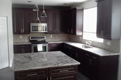Klassisk inredning av ett mellanstort kök, med en undermonterad diskho, luckor med upphöjd panel, skåp i mörkt trä, granitbänkskiva, grått stänkskydd, stänkskydd i mosaik, rostfria vitvaror, klinkergolv i keramik, en köksö och grått golv