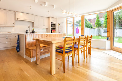 Immagine di una cucina contemporanea con ante in stile shaker, ante beige e parquet chiaro
