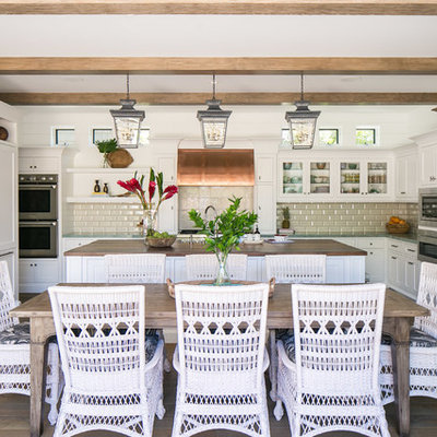 Inspiration for a large tropical u-shaped medium tone wood floor and brown floor eat-in kitchen remodel in Orange County with shaker cabinets, white cabinets, wood countertops, subway tile backsplash, stainless steel appliances, an island, brown countertops and beige backsplash