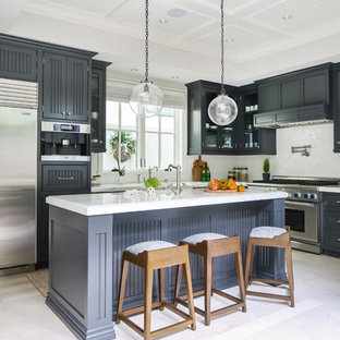 Design ideas for a transitional l-shaped kitchen in Orange County with louvered cabinets, grey cabinets, white splashback, stainless steel appliances, with island, white floor and white benchtop.