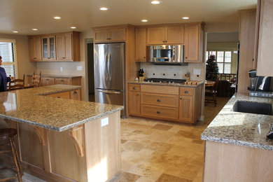 Example of a large classic u-shaped limestone floor and beige floor eat-in kitchen design in San Luis Obispo with an undermount sink, shaker cabinets, light wood cabinets, granite countertops, beige backsplash, ceramic backsplash, stainless steel appliances and an island