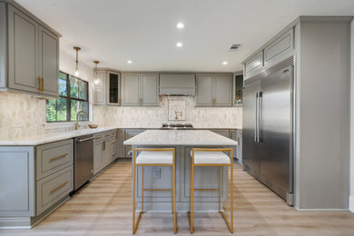 Inspiration for a large transitional u-shaped light wood floor and brown floor eat-in kitchen remodel in New Orleans with an undermount sink, flat-panel cabinets, gray cabinets, quartzite countertops, white backsplash, marble backsplash, stainless steel appliances, an island and white countertops