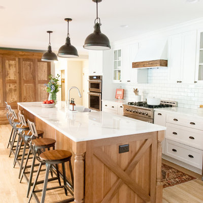 Inspiration for a farmhouse galley light wood floor and beige floor kitchen remodel in Houston with shaker cabinets, an island, white cabinets, white backsplash, subway tile backsplash and stainless steel appliances