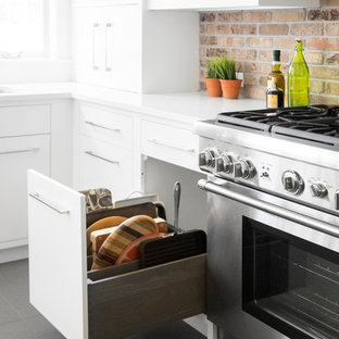 Mid-sized transitional eat-in kitchen photos - Inspiration for a mid-sized transitional l-shaped porcelain tile and gray floor eat-in kitchen remodel in New York with a single-bowl sink, flat-panel cabinets, white cabinets, quartzite countertops, brown backsplash, brick backsplash, stainless steel appliances and an island
