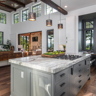 Ispirazione per una grande cucina stile rurale con lavello sottopiano, ante in stile shaker, ante bianche, top in granito, paraspruzzi bianco, paraspruzzi a finestra, elettrodomestici in acciaio inossidabile, parquet scuro, isola, pavimento marrone e top nero