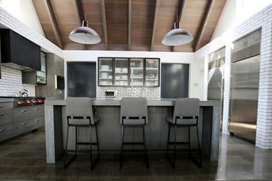 Inspiration for a large industrial u-shaped limestone floor open concept kitchen remodel in San Diego with an island, flat-panel cabinets, gray cabinets, concrete countertops, white backsplash, stainless steel appliances, an integrated sink and subway tile backsplash