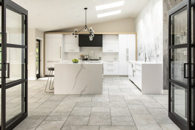 Example of a large minimalist l-shaped limestone floor and gray floor eat-in kitchen design in San Francisco with a farmhouse sink, flat-panel cabinets, white cabinets, quartz countertops, white backsplash, subway tile backsplash, paneled appliances, an island and white countertops