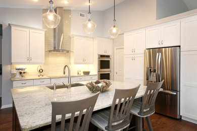 Example of a mid-sized beach style l-shaped medium tone wood floor and brown floor eat-in kitchen design in Jacksonville with a single-bowl sink, recessed-panel cabinets, white cabinets, granite countertops, gray backsplash, glass tile backsplash, stainless steel appliances and an island