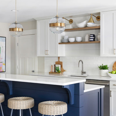 Open concept kitchen - coastal galley ceramic tile open concept kitchen idea in Minneapolis with an undermount sink, shaker cabinets, white cabinets, white backsplash, subway tile backsplash, stainless steel appliances, an island, white countertops and quartz countertops