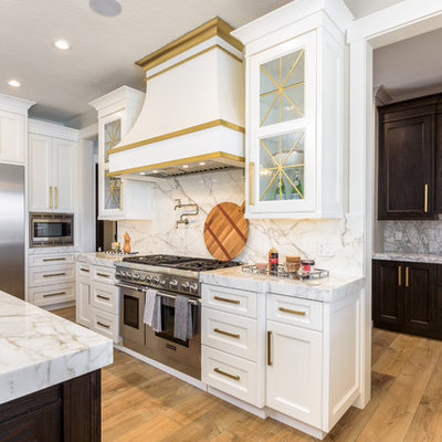 Inspiration for a large transitional single-wall medium tone wood floor and brown floor enclosed kitchen remodel in Salt Lake City with a farmhouse sink, shaker cabinets, white cabinets, marble countertops, gray backsplash, marble backsplash, stainless steel appliances, gray countertops and two islands