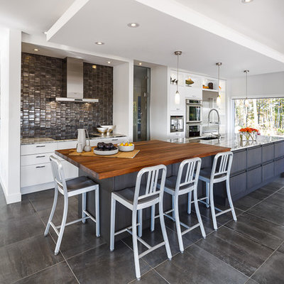 Eat-in kitchen - large contemporary galley porcelain tile and gray floor eat-in kitchen idea in Ottawa with white cabinets, wood countertops, metallic backsplash, an island, metal backsplash, an undermount sink, stainless steel appliances and flat-panel cabinets