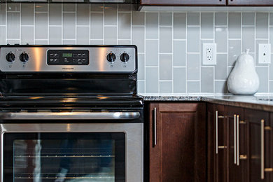 Kitchen - modern kitchen idea in Ottawa with recessed-panel cabinets, brown cabinets, granite countertops, gray backsplash and stainless steel appliances