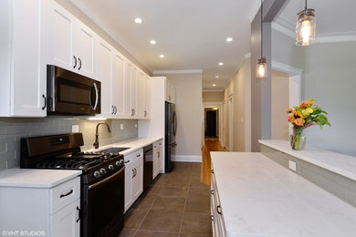 Photo of a small traditional galley kitchen/diner in Chicago with a submerged sink, shaker cabinets, white cabinets, composite countertops, grey splashback, glass tiled splashback, stainless steel appliances, ceramic flooring and an island.