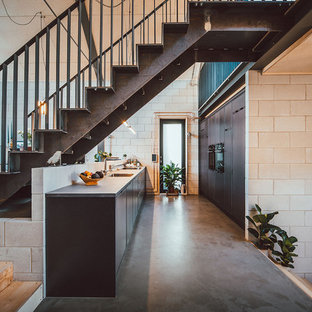 Design ideas for a medium sized urban galley open plan kitchen in Other with a built-in sink, flat-panel cabinets, grey cabinets, stainless steel worktops, integrated appliances, concrete flooring, no island, grey floors and grey worktops.
