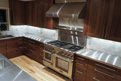 Example of a mid-sized u-shaped light wood floor kitchen design in Denver with dark wood cabinets, gray backsplash, stone slab backsplash, stainless steel appliances and an island