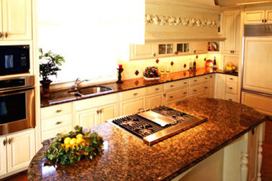 Example of a large l-shaped medium tone wood floor open concept kitchen design in Atlanta with a double-bowl sink, white cabinets, granite countertops, ceramic backsplash, paneled appliances and an island