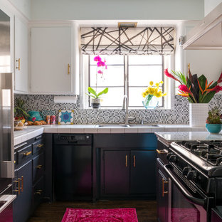 This is an example of a small eclectic u-shaped separate kitchen in Los Angeles with a double-bowl sink, flat-panel cabinets, white cabinets, tile benchtops, multi-coloured splashback, mosaic tile splashback, stainless steel appliances, vinyl floors, no island, brown floor and white benchtop.