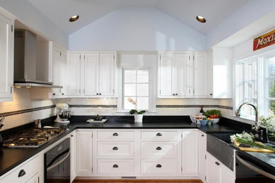 Inspiration for a mid-sized timeless u-shaped medium tone wood floor and brown floor enclosed kitchen remodel in Chicago with a farmhouse sink, shaker cabinets, white cabinets, soapstone countertops, white backsplash, porcelain backsplash, stainless steel appliances and no island