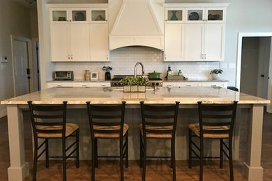 オースティンにある高級な広いトランジショナルスタイルのおしゃれなキッチン (アンダーカウンターシンク、シェーカースタイル扉のキャビネット、白いキャビネット、珪岩カウンター、白いキッチンパネル、サブウェイタイルのキッチンパネル、シルバーの調理設備、濃色無垢フローリング、茶色い床、グレーのキッチンカウンター) の写真