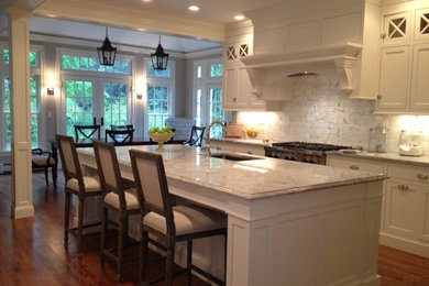 Inspiration for a large timeless u-shaped medium tone wood floor eat-in kitchen remodel in Boston with shaker cabinets, white cabinets, white backsplash, stainless steel appliances, an island and a drop-in sink