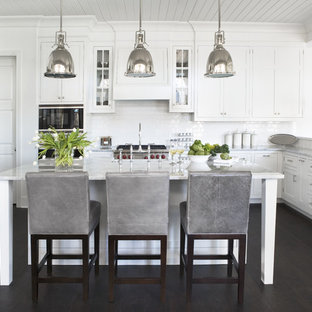 Inspiration for a large contemporary u-shaped dark wood floor kitchen remodel in Other with stainless steel appliances, shaker cabinets, white cabinets, marble countertops, white backsplash, subway tile backsplash and an island