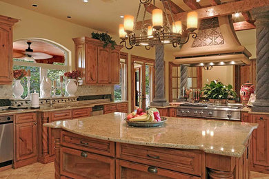 Example of a large farmhouse u-shaped travertine floor and beige floor eat-in kitchen design in Austin with an undermount sink, recessed-panel cabinets, medium tone wood cabinets, granite countertops, beige backsplash, stone tile backsplash, stainless steel appliances and an island