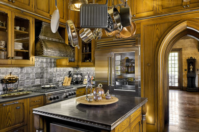 Ornate dark wood floor kitchen photo in Portland Maine with recessed-panel cabinets, medium tone wood cabinets, gray backsplash, stainless steel appliances and an island