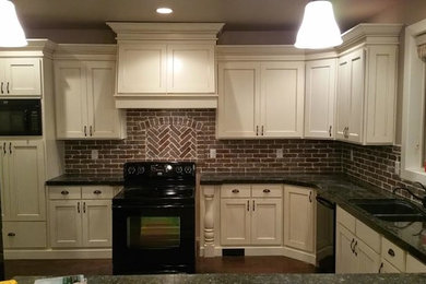 Example of a medium tone wood floor kitchen design in Salt Lake City with an undermount sink, recessed-panel cabinets, white cabinets, granite countertops, red backsplash and black appliances