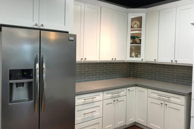 Eat-in kitchen - small traditional l-shaped laminate floor eat-in kitchen idea in Los Angeles with shaker cabinets, white cabinets, quartz countertops, gray backsplash, glass tile backsplash, stainless steel appliances and no island