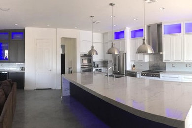 Large minimalist l-shaped concrete floor open concept kitchen photo in Las Vegas with a double-bowl sink, shaker cabinets, white cabinets, marble countertops, stainless steel appliances and an island