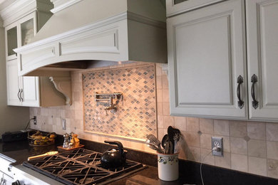 Example of a large classic kitchen design in Baltimore with raised-panel cabinets, white cabinets, granite countertops, beige backsplash, stone tile backsplash and stainless steel appliances