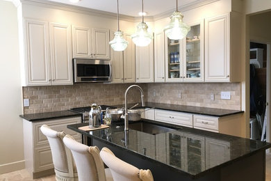 Open concept kitchen - mid-sized traditional l-shaped travertine floor and beige floor open concept kitchen idea in Denver with an undermount sink, raised-panel cabinets, white cabinets, granite countertops, beige backsplash, ceramic backsplash, stainless steel appliances and an island