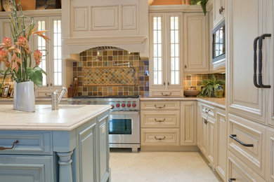Example of a large transitional l-shaped porcelain tile and beige floor enclosed kitchen design in New York with raised-panel cabinets, beige cabinets, quartzite countertops, multicolored backsplash, porcelain backsplash, an island, an undermount sink, stainless steel appliances and beige countertops
