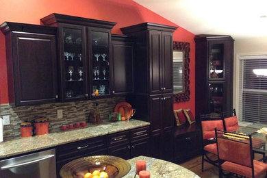 Klassisk inredning av ett mellanstort kök, med luckor med upphöjd panel, skåp i mörkt trä, granitbänkskiva, brunt stänkskydd, stänkskydd i stickkakel, rostfria vitvaror, mellanmörkt trägolv och en köksö