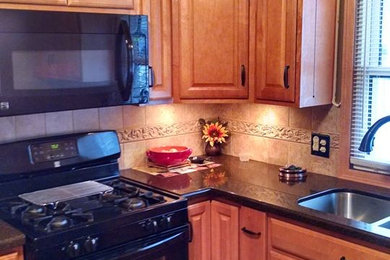 Example of a l-shaped ceramic tile kitchen design in Minneapolis with a double-bowl sink, raised-panel cabinets, medium tone wood cabinets and black appliances