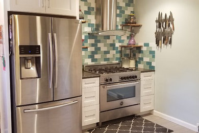 Example of a mid-sized transitional vinyl floor and gray floor open concept kitchen design in Orange County with an undermount sink, shaker cabinets, white cabinets, solid surface countertops, blue backsplash, subway tile backsplash, stainless steel appliances and a peninsula